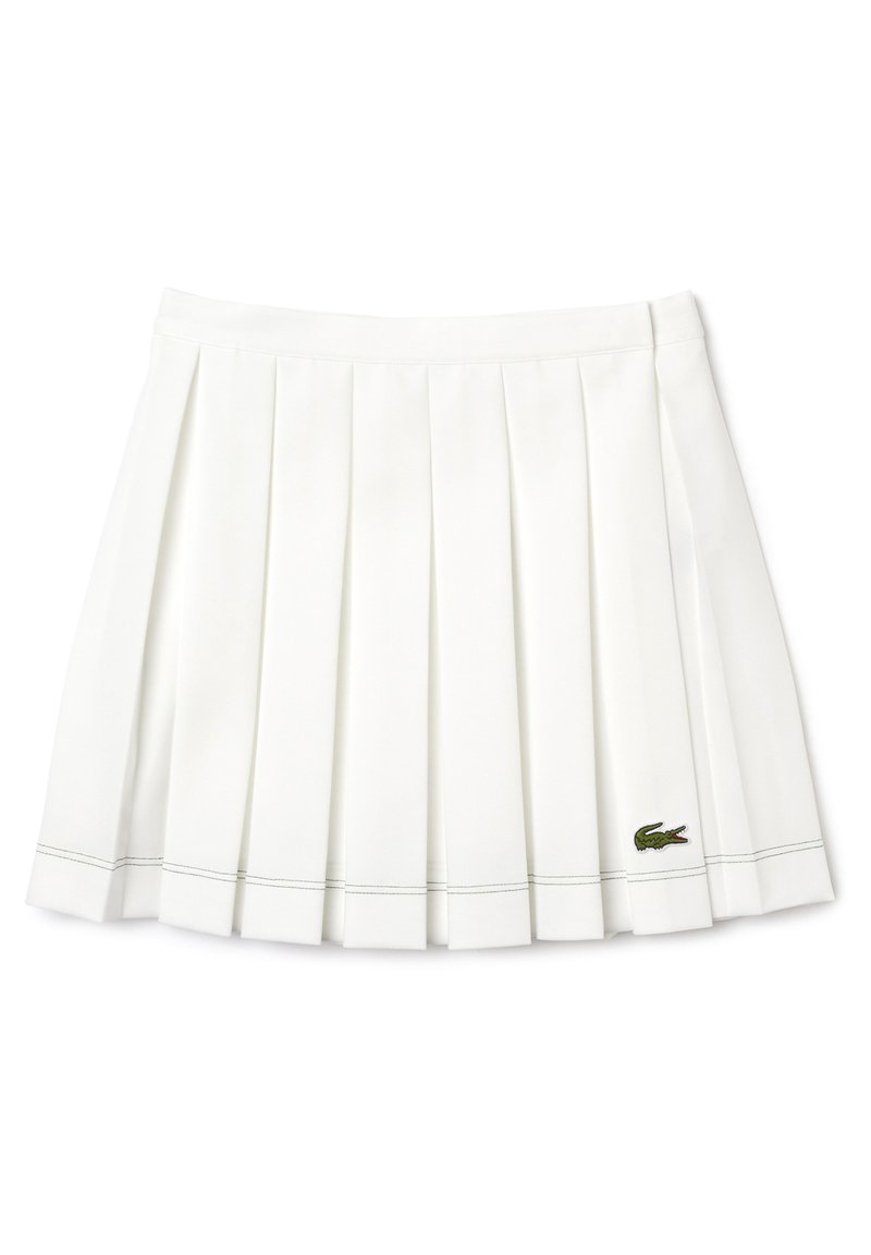 Falda blanca con pliegues y una textura suave, que presenta costuras en contraste y un pequeño logo de cocodrilo verde en la parte inferior derecha.