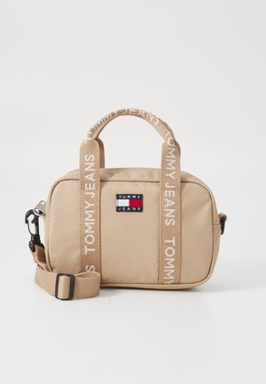 Beige stoffen handtas met dubbele bovenhandvatten en een verstelbare schouderband. Voorzien van een logopatch, gestructureerd materiaal en accenten van het merk op de schouderband.