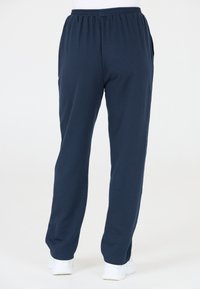 Marina blå sweatsbyxor tillverkade av mjukt tyg, med elastisk midja, sidofickor och en avslappnad passform som smalnar av vid anklarna.