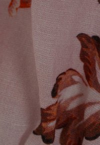 Helles rosa Gewebe mit einem floralen Muster in Brauntönen und Orange, mit einer glatten, texturierten Oberfläche.