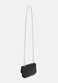 Borsa a tracolla rettangolare nera con superficie testurizzata e lungo manico a catena argentata appesa su sfondo bianco.