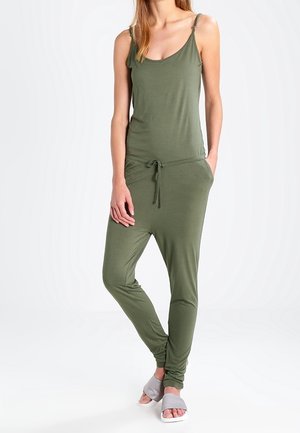 Combinaison vert olive avec bretelles spaghetti réglables, encolure dégagée, taille à cordon de serrage et jambes fuselées, associée à des sandales glissantes gris clair.