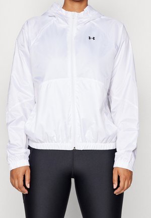 Weißes Sportjacke mit Kapuze und Reißverschluss, elastischen Bündchen und Bund, getragen über schwarzen Leggings, mit kleinem schwarzem Logo auf der Brust.