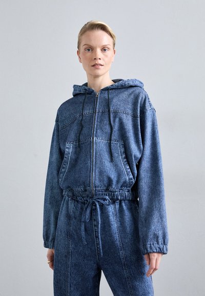 Hoodie en denim avec une fermeture éclair à l'avant, capuche avec cordon de serrage et poche kangourou. Lavage bleu foncé, coupe décontractée avec des coutures visibles et une taille élastique.