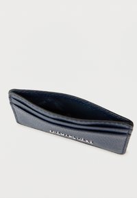 Granatowy etui na karty wykonane z teksturowanej skóry, wyposażone w wiele przegródek na karty oraz subtelne srebrne logo na przodzie.