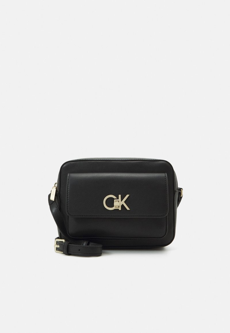 Černá kožená crossbody taška se zlatým logem, obdélníkový tvar, klopový uzávěr, nastavitelný popruh, hladká textura a minimalistický design.