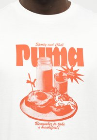 Άσπρο πουκάμισο με πορτοκαλί γραφικό που δείχνει είδη πρωινού, κείμενο "Sporty and Chill Puma", "Πιο γρήγορη παράδοση" και "Να θυμάσαι να παίρνεις πρωινό."