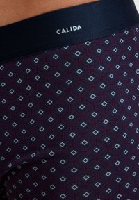 Boxers in dark navy with a geometric diamond pattern in white and burgundy. Soft fabric, elastic waistband with "CALIDA" logo.