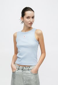 Ανοιχτό μπλε ριγωτό αμάνικο τοπ με στρογγυλή λαιμόκοψη και ετικέτα με λογότυπο, συνδυασμένο με ασημί τζιν σορτς με μπροστινές τσέπες.