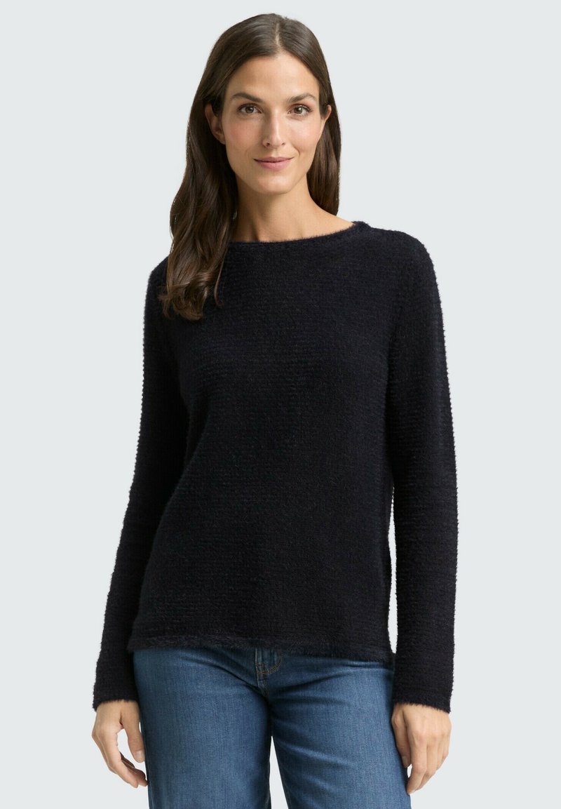 Black, textured pullover sweater with long sleeves and a round neckline, paired with blue denim jeans. Informal and cozy fit.