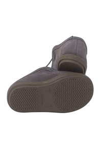 Scarpa in suede grigia con suola in gomma texturizzata, dotata di punta arrotondata e tacco basso. I lacci sono visibili lungo la parte superiore.