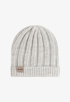 Lichtgrijze gebreide beanie met een geribbelde structuur, een omgeslagen rand en een klein stoffen label met de tekst "KNIT FACTORY" aan de zijkant.