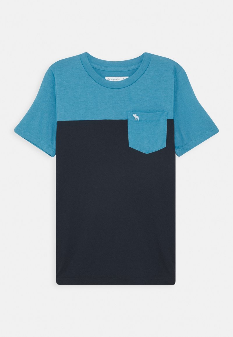 Camiseta de manga corta con cuello redondo, mitad superior y mangas en verde azulado, mitad inferior en azul marino y bolsillo en el pecho verde azulado con un pequeño logo blanco.