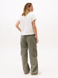 White short-sleeve top and loose-fitting olive green cargo pants with side pockets, standing on a neutral background.