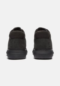 Zapatos de ante negros con textura suave, forma redondeada y detalle de logo en relieve en el talón. Suela de goma duradera con bandas de tracción.