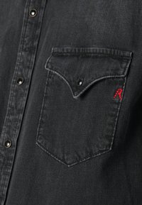 Zwarte denim shirt met een borstzak met een ronde klep, zwarte knopen en een klein rood geborduurd logo op de zak.