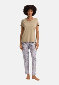 Ljusbeige V-ringad T-shirt i kombination med blommönstrade lavendelpyjamasbyxor som har en mjuk textur och en avslappnad passform.