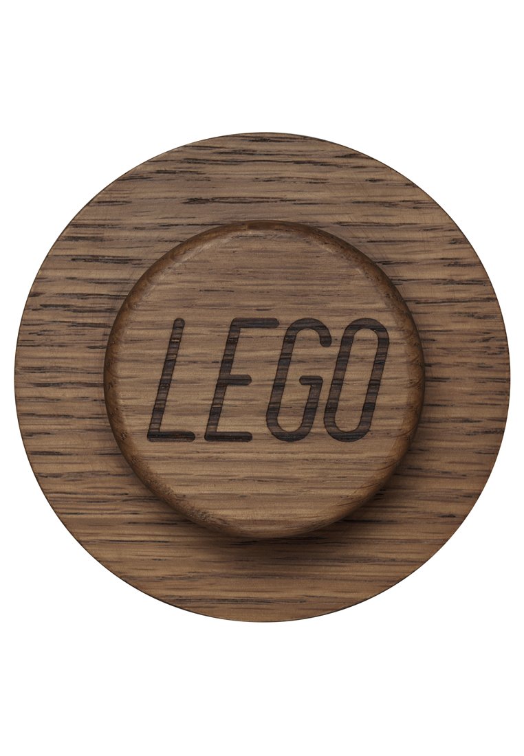 Holzuntersetzer mit kreisförmiger Form, graviert mit "LEGO", vor einem strukturierten, hellbraunen Holzsockel mit sichtbaren Maserungen.