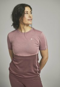 Short-sleeve athletic top in light and dark pink shades, featuring a crew neck and a subtle logo. Smooth texture, fitted design, and side seams.