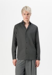 Camicia grigia scura con colletto a punta, maniche lunghe e una texture liscia. Presenta bottoni neri e orlo dritto.