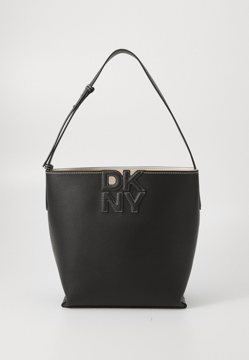 Melna ādas spainīša soma ar iepresētu "DKNY" logo, regulējamu siksnu un kontrastējošiem diegiem. Gluda tekstūra ar strukturētu formu.