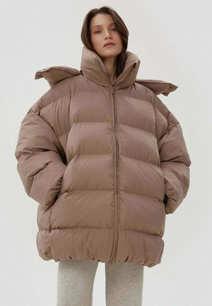 Brązowa pikowana kurtka puchowa z wysokim kołnierzem, grubymi przeszyciami i przednim zamkiem błyskawicznym. Lekki materiał o gładkiej fakturze i luźnym, oversize'owym kroju.