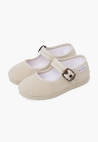 Zapatos Mary Jane de tela beige con superficie texturizada, punteras redondeadas y una correa con hebilla para un cierre seguro. Forro de tela suave, suelas planas.