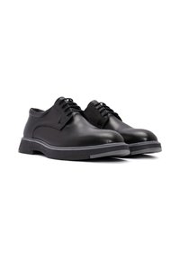 Zwarte leren schoenen met een gladde afwerking, ronde neus, vetersluiting en een grijze rubberen zool met een lichte hak.