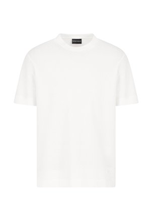 T-shirt blanc à manches courtes en matériau texturé avec un col rond. Présente une étiquette logo discrète en bas à droite.