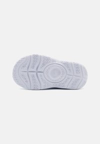 Semelle de sneaker en caoutchouc blanc avec un motif de texture antidérapant. Présente un logo circulaire au centre et des motifs en ondulation pour la traction.