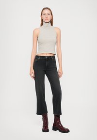 Light gray and white striped, high-neck crop top paired with black jeans and glossy burgundy ankle boots. Simple, modern design elements.