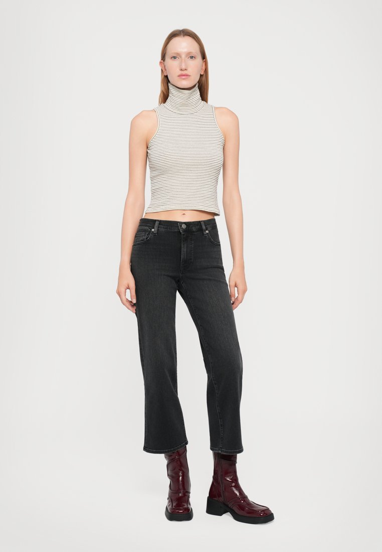 Un crop top à col haut rayé gris clair et blanc, associé à un jean noir et des bottines bourgogne brillantes. Élément de design simple et moderne.