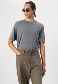 Gray cotton T-shirt with a relaxed fit and short sleeves, paired with light brown denim jeans featuring a straight cut and distressed texture.