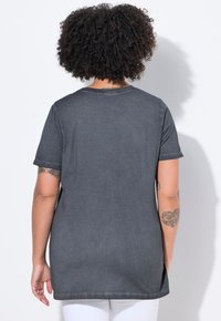 Mørkegrå t-shirt med korte ærmer, rund halsudskæring og afslappet pasform. Har synlige sømme og sideslidser for ekstra bevægelsesfrihed.