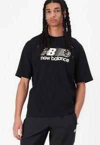 Črna bombažna majica s kratkimi rokavi, ki ima bel logo "New Balance" in grafiko košarke čez prsni del.