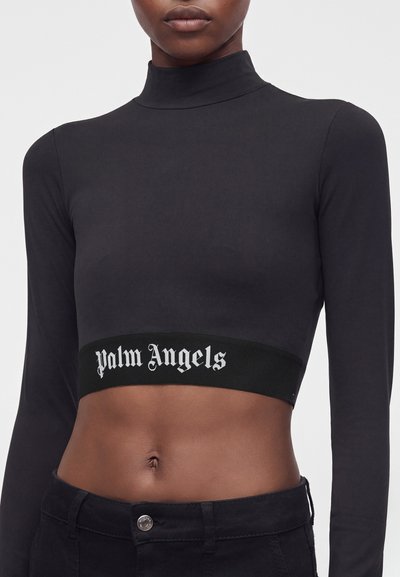 Άτομο που φοράει μαύρο cropped top με μακριά μανίκια και ψηλό λαιμό με το κείμενο "Palm Angels" στη κάτω ταινία, συνδυασμένο με μαύρο παντελόνι.