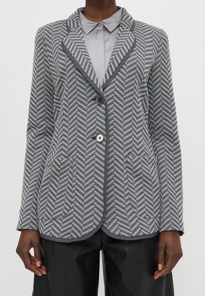 Grijze herringbone blazer met een gelapte kraag, sluiting met twee knopen en voorzakken, met een gestructureerde stof en contrasterende afwerking.