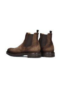 Bottes Chelsea en suede marron avec panneaux élastiques latéraux, detailing brogue décoratif et semelles en caoutchouc robustes. Caractéristiques de languettes pour un enfilage facile.
