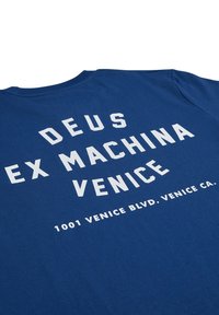 Blue cotton t-shirt featuring large white text that reads "DEUS EX MACHINA VENICE" and a smaller address line beneath. Crew neck design.