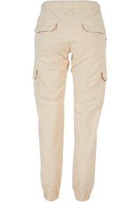 Béžové cargo kalhoty s elastickým pasem a manžetami, se založenými kapsami na zadní a boční straně, zobrazené ze zadní strany.