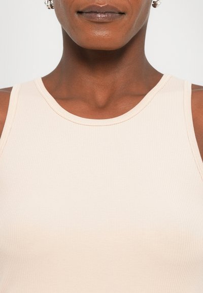Beige ribbed tank top featuring a classic round neck and snug fit, made from a stretchy cotton blend for comfort.
