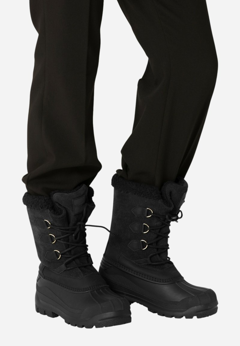 Černé voděodolné sněhové boty s polstrovaným kožešinovým límcem, šněrováním vpředu, gumovou podešví a akcenty z kovového hardwaru.