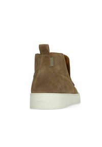 Bottes montantes en suède marron avec une semelle en caoutchouc blanche, dotées d'une languette au dos et d'un branding subtil sur le talon.