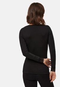 Top negro de manga larga hecho de tela suave, con acentos de encaje en los puños y un diseño ajustado. Vista trasera, con un escote redondeado.