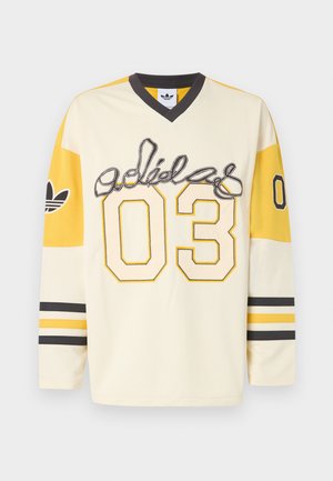 Maillot de sport Adidas à manches longues de couleur crème et jaune avec script "adidas", numéro 03 sur le devant et les manches, col en V noir et poignets rayés.