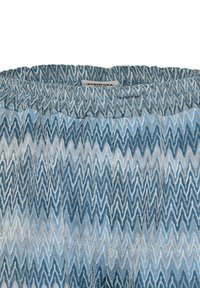 Tessuto testurizzato con motivo a zigzag in tonalità di blu, bianco e grigio. Vita elastica con un'etichetta che riporta "ACANTHORA."