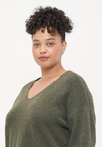 Olíva zöld, túlméretezett pulóver puha, texturált anyagból, V-kivágással és széles ujjakkal, laza, modern fazonnal.