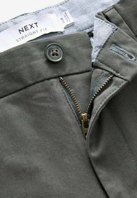 Pantaloni in cotone grigi con vestibilità dritta, zip metallica, chiusura con bottone rotondo e etichetta interna sulla vita.