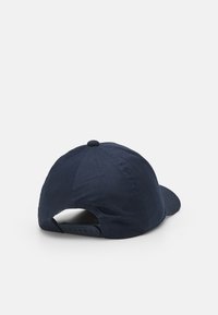 Cappellino da baseball blu navy con visiera curva, texture morbida, cinturino regolabile sul retro e un bottone in tessuto centrale nella parte superiore.