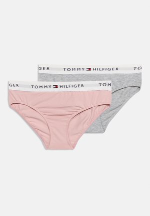 Divas sieviešu kokvilnas biksītes, viena rozā un viena pelēka, katrai ar baltu jostas daļu, uz kuras redzams "Tommy Hilfiger" nosaukums un logo.